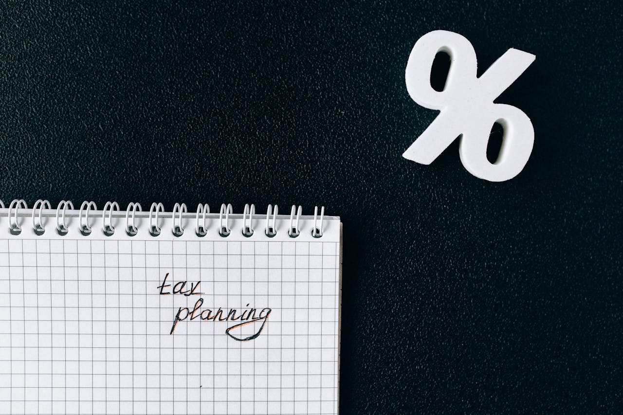 about-01 A notebook with tax planning written on a grid paper next to a percent symbol on a black background.