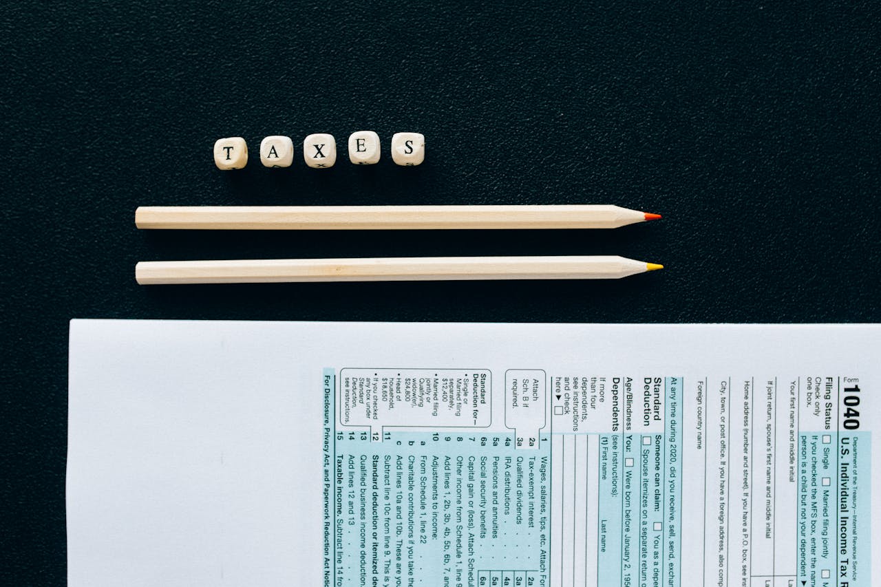home-services-02 Flat lay of 1040 tax form with pencils and TAXES blocks on black background.